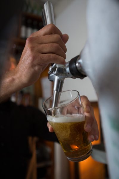 Brewer filling beer in beer glass from beer pump in bar